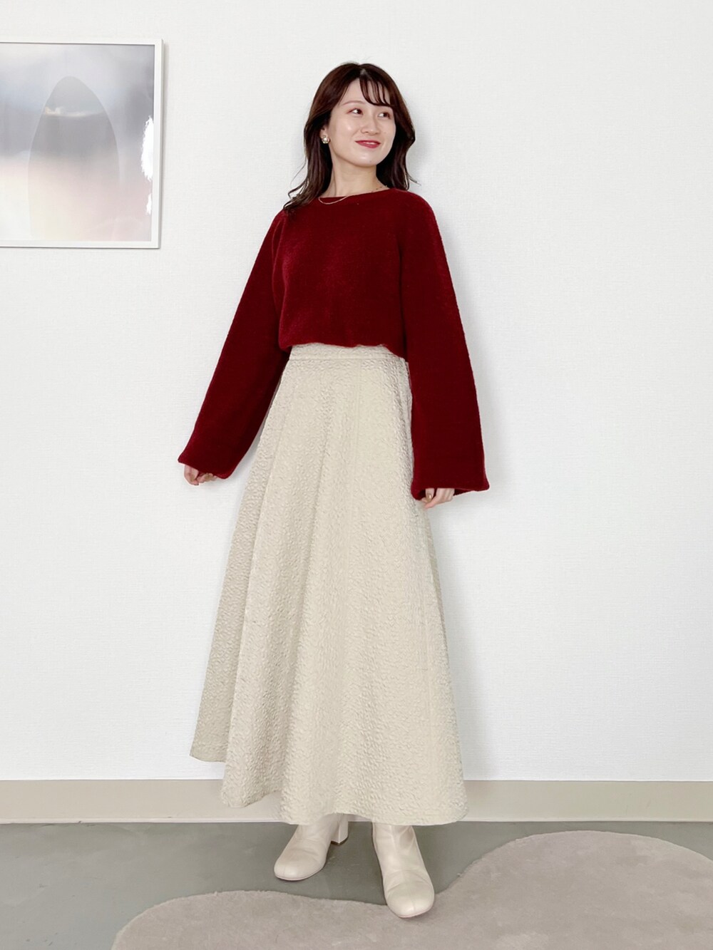 レッド系のニット/セーター、ホワイト系のブルゾン、ホワイト系のスカートを着用したレディースの冬コーディネートの3枚目の写真