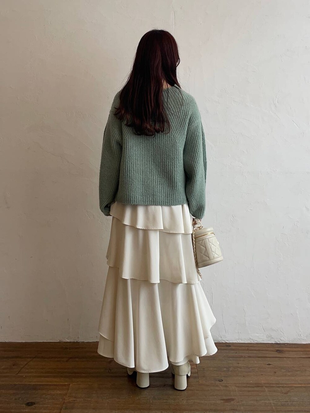 ホワイト系のブーツ、ホワイト系のスカート、ホワイト系のショルダーバッグを着用したレディースの冬コーディネートの2枚目の写真