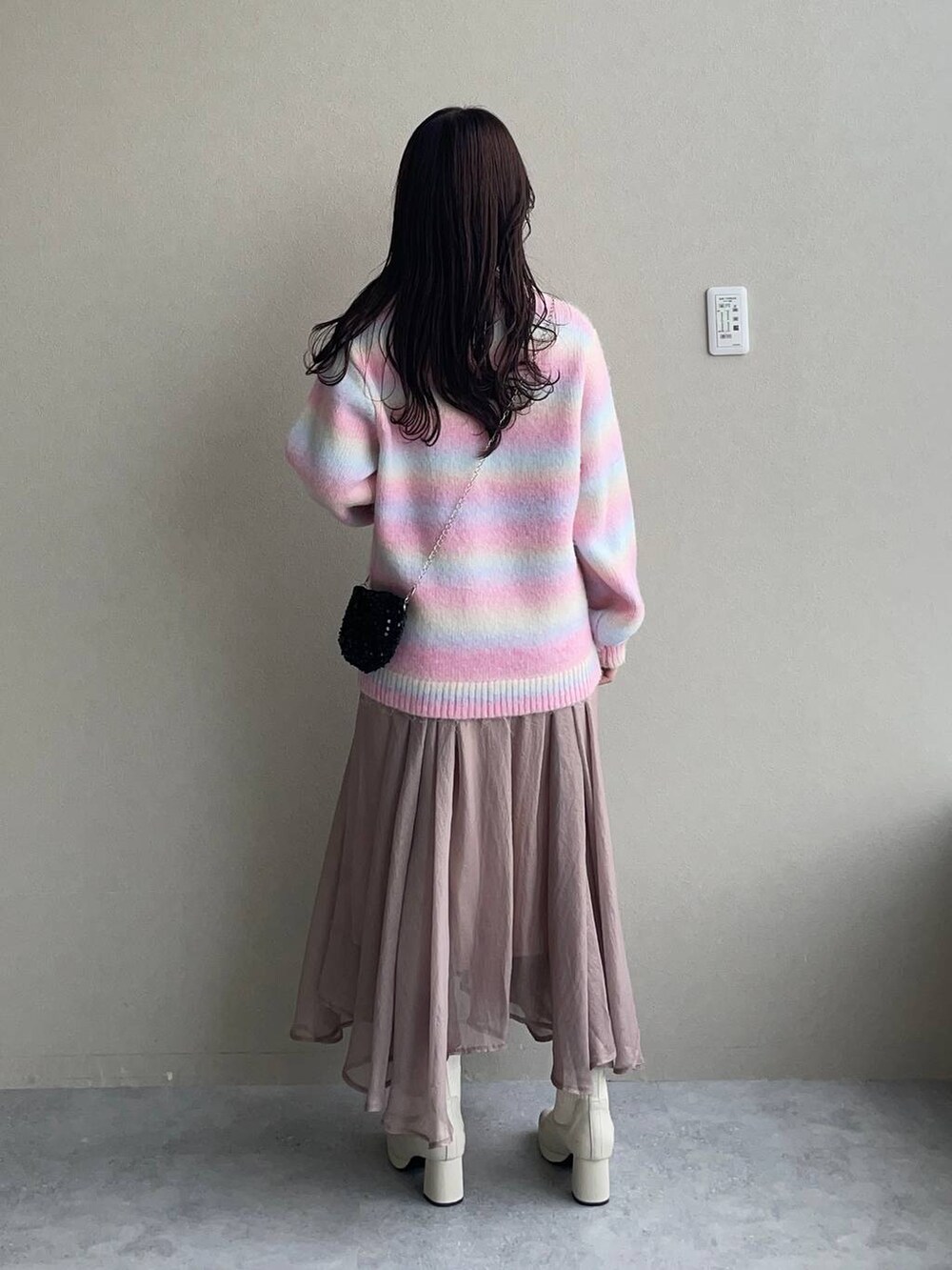 ホワイト系のブーツ、ベージュ系のスカート、ブラック系のショルダーバッグを着用したレディースの秋コーディネートの2枚目の写真