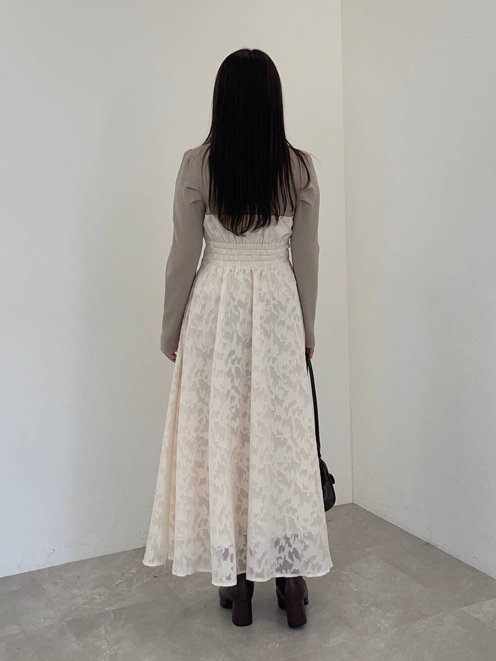 ブラウン系のブーツ、ブラウン系のハンドバッグ、ホワイト系のワンピースを着用したレディースの冬コーディネートの2枚目の写真