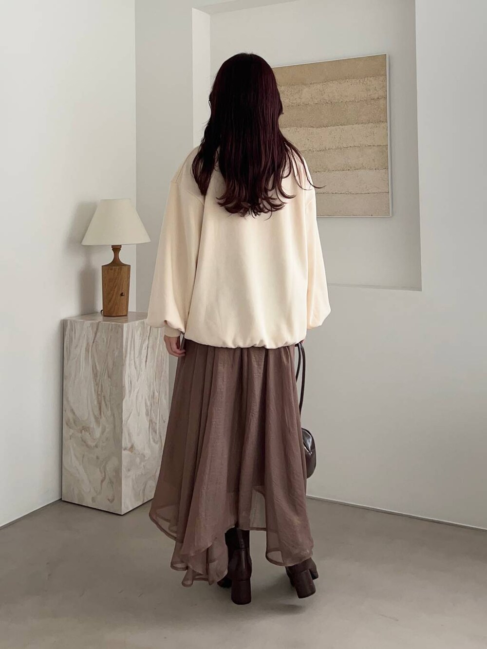 ブラウン系のブーツ、ホワイト系のスウェット、ブラウン系のハンドバッグを着用したレディースの冬コーディネートの2枚目の写真