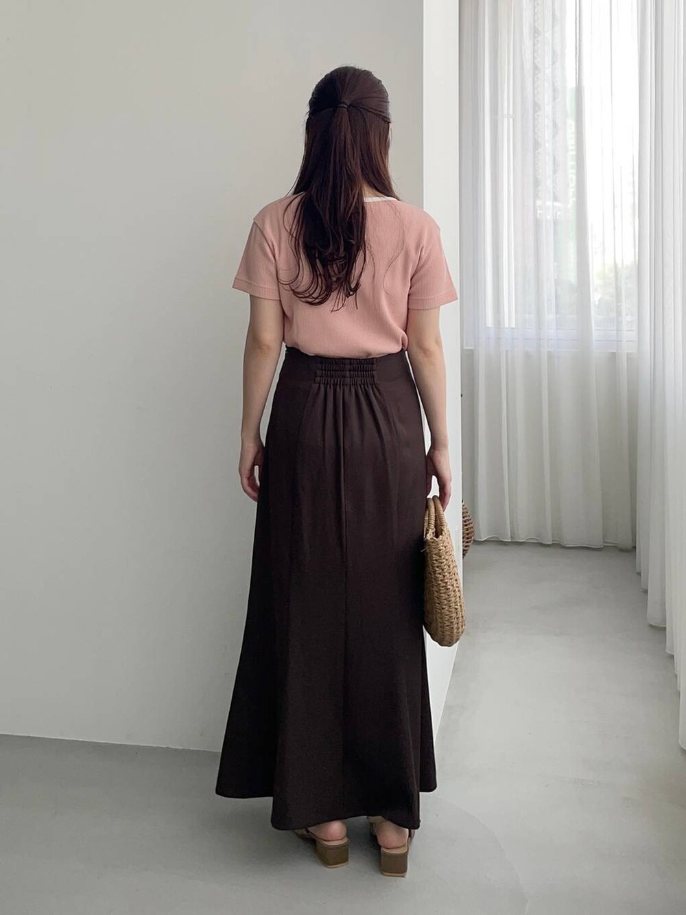 ブラウン系のサンダル、ブラウン系のかごバッグ、ピンク系のTシャツ/カットソーを着用したレディースの春コーディネートの2枚目の写真