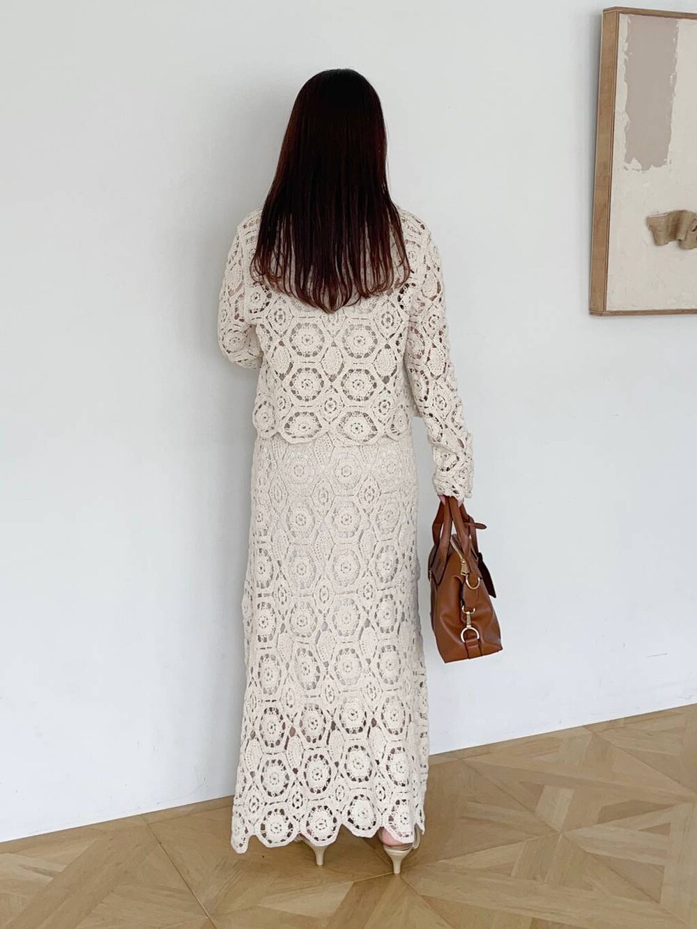 ゴールド系のパンプス、ホワイト系のカーディガン/ボレロ、ホワイト系のスカートを着用したレディースの夏コーディネートの2枚目の写真