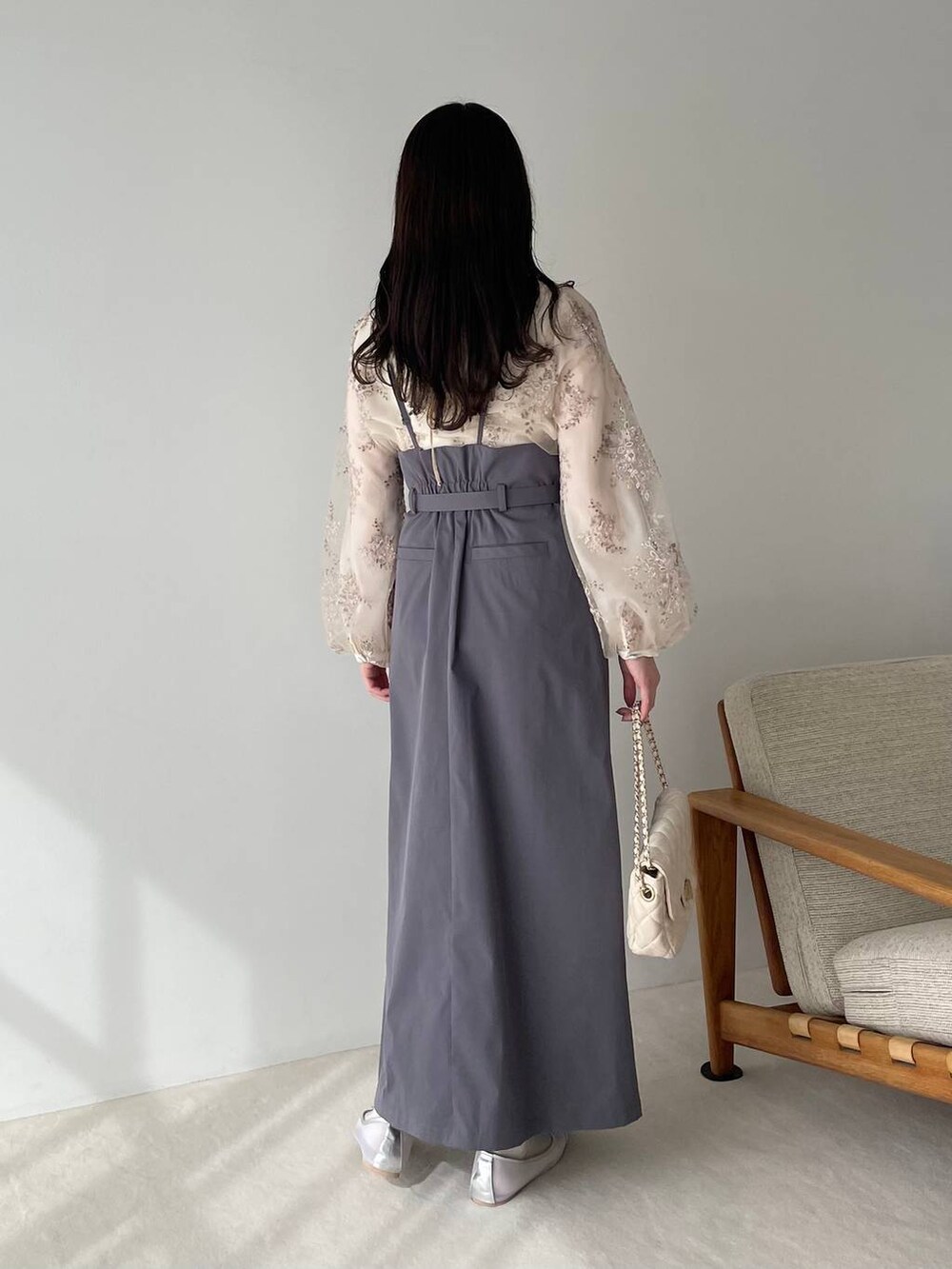 シルバー系のバレエシューズ、ホワイト系のショルダーバッグ、グレー系のスカートを着用したレディースの冬コーディネートの2枚目の写真