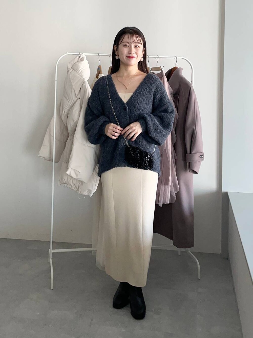 ブラック系のブーツ、ホワイト系のワンピース、グレー系のカーディガン/ボレロを着用したレディースの冬コーディネートの3枚目の写真