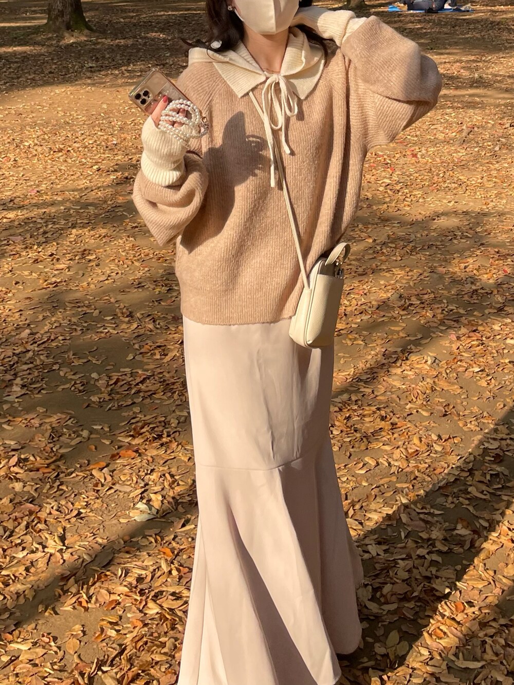 ベージュ系のニット/セーター、ホワイト系のショルダーバッグ、ホワイト系のニットキャップ/ビーニーを着用したレディースの秋コーディネートの2枚目の写真