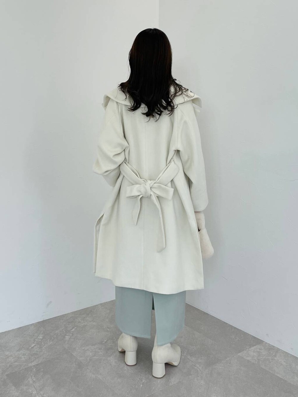 ホワイト系のブーツ、ホワイト系のハンドバッグ、ホワイト系のチェスターコートを着用したレディースの冬コーディネートの2枚目の写真