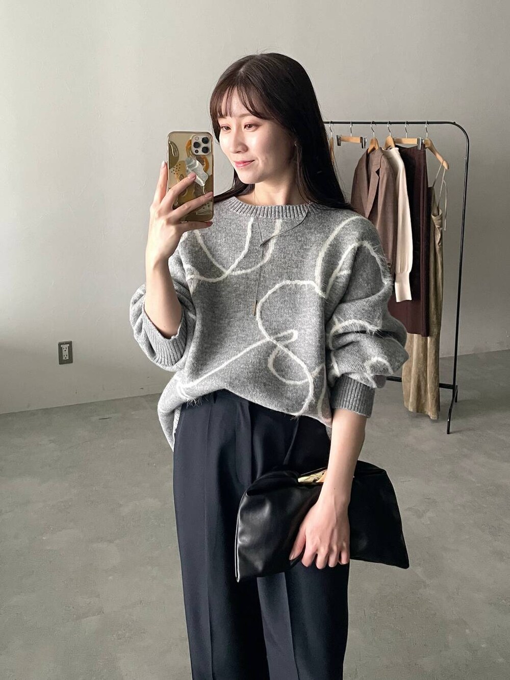 ブラック系のハンドバッグ、グレー系のニット/セーター、ブルー系のスラックスを着用したレディースの秋コーディネートの3枚目の写真