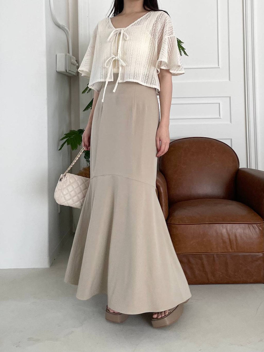 ベージュ系のサンダル、ホワイト系のカーディガン/ボレロ、ホワイト系のショルダーバッグを着用したレディースの夏コーディネートの4枚目の写真