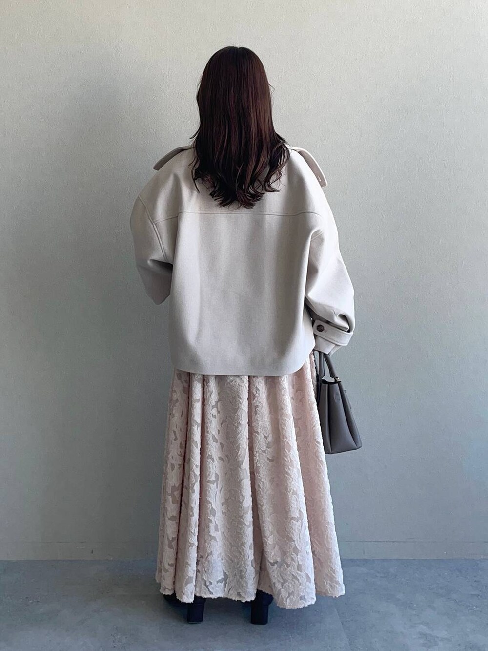 ホワイト系のピーコート、ベージュ系のショルダーバッグ、ブラウン系のブーツを着用したレディースの冬コーディネートの2枚目の写真