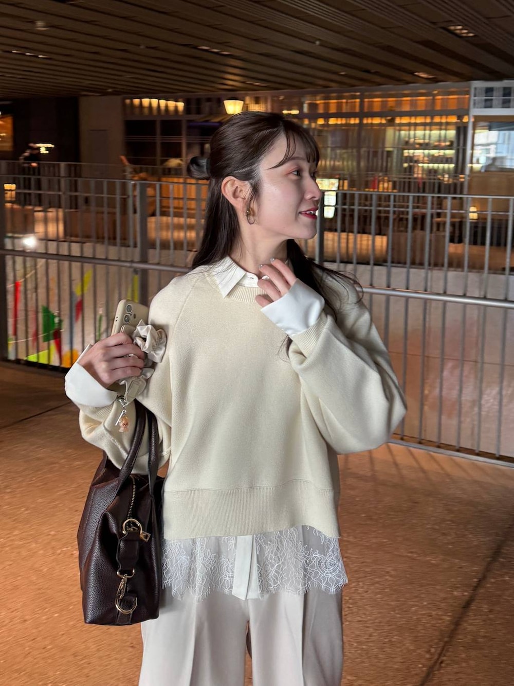 ブラウン系のボストンバッグ、ホワイト系のスラックス、ホワイト系のニット/セーターを着用したレディースの冬コーディネートの2枚目の写真