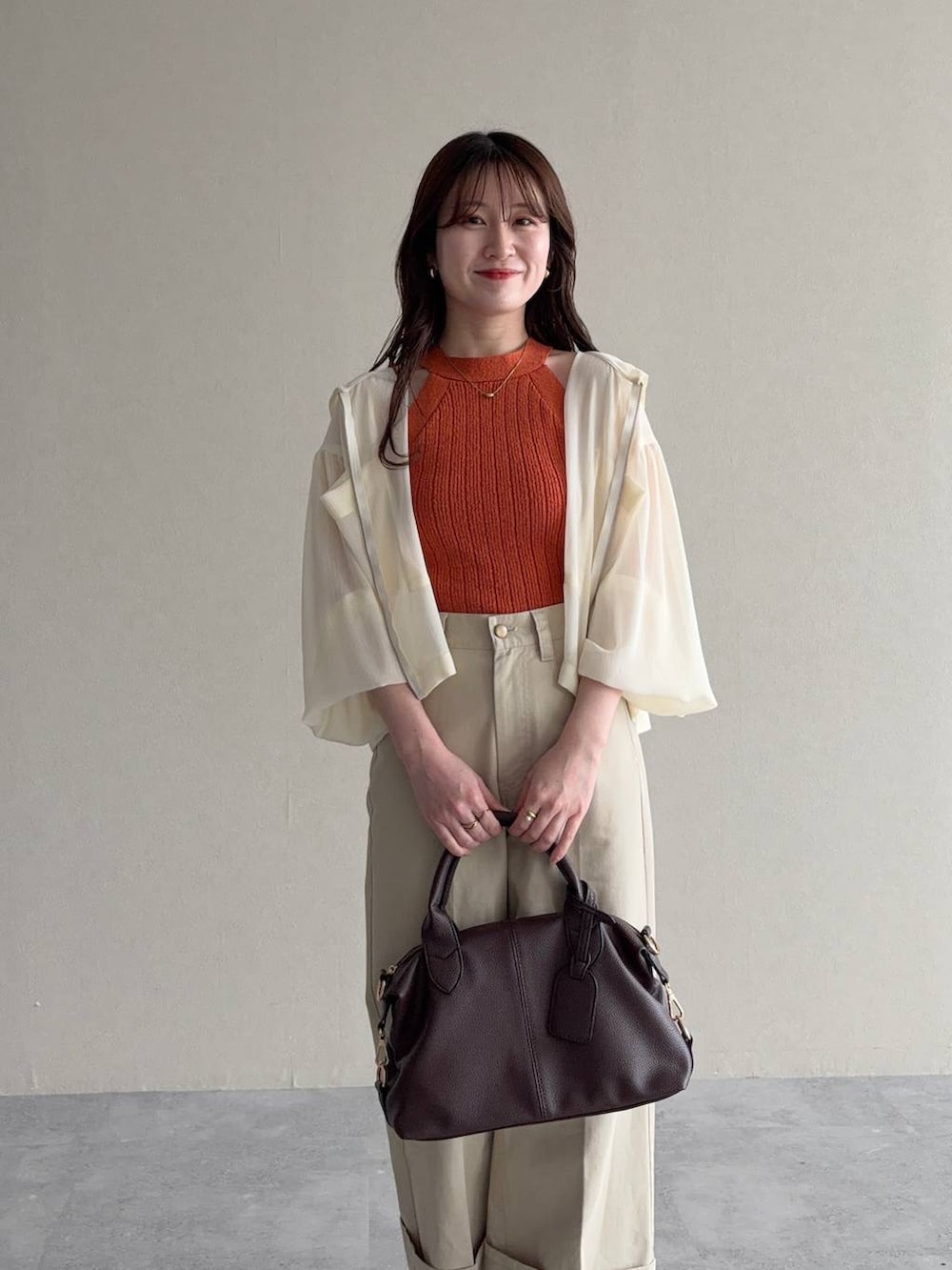 ホワイト系のパーカー、ブラウン系のボストンバッグ、ブラウン系のサンダルを着用したレディースの春コーディネートの3枚目の写真