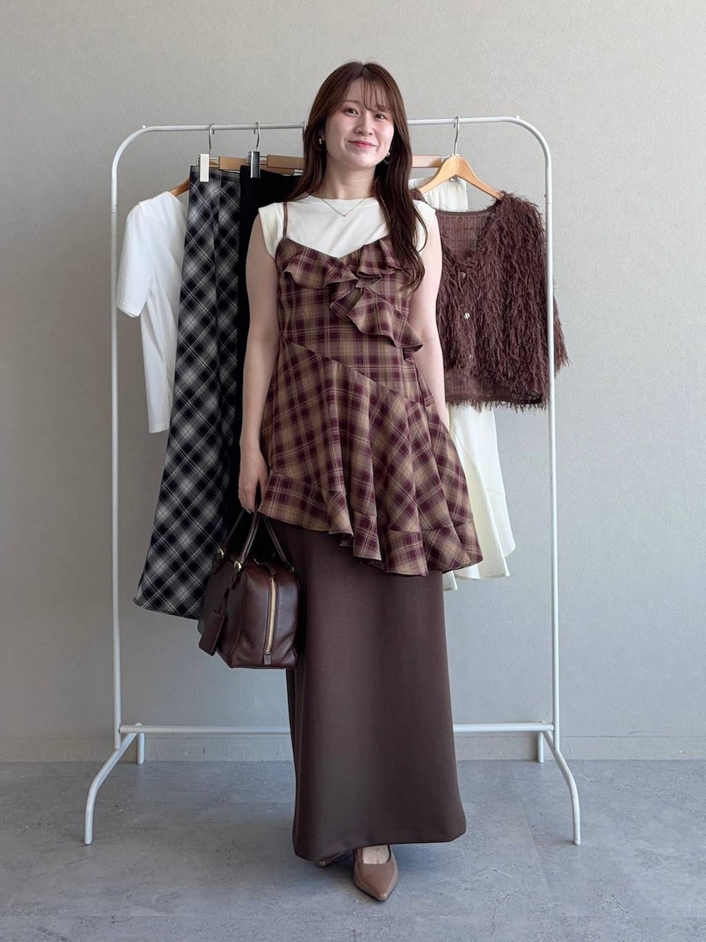 ホワイト系のニット/セーター、ブラウン系のスカート、レッド系のシャツ/ブラウスを着用したレディースの秋コーディネートの3枚目の写真