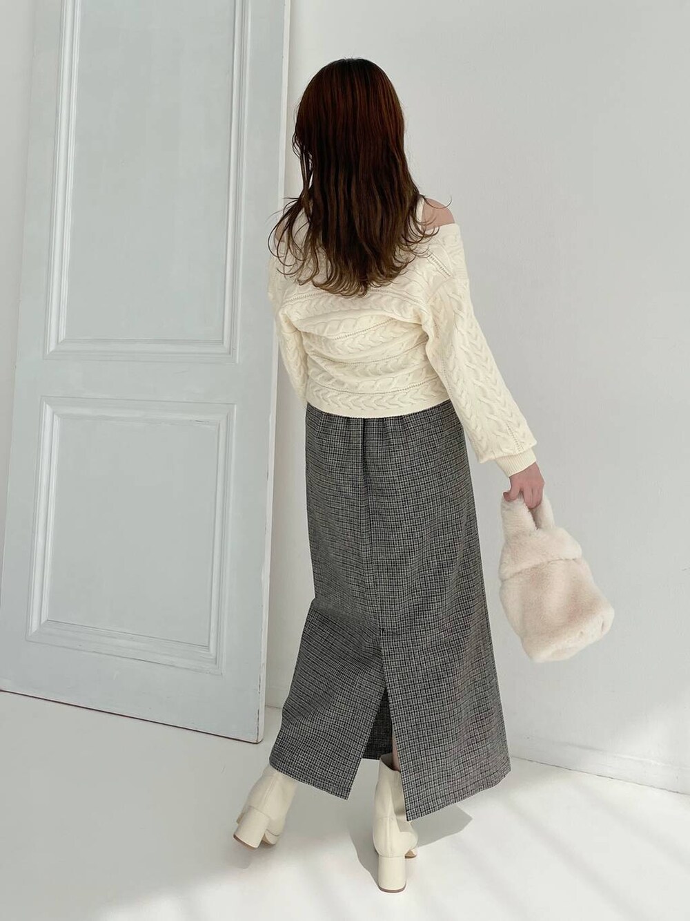 ホワイト系のブーツ、ホワイト系のハンドバッグ、ブラック系のスカートを着用したレディースの秋コーディネートの2枚目の写真