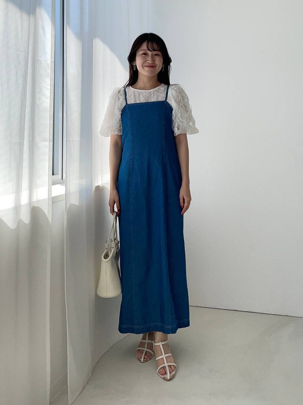 ホワイト系のハンドバッグ、ブルー系のワンピース、ホワイト系のサンダルを着用したレディースの夏コーディネートの2枚目の写真