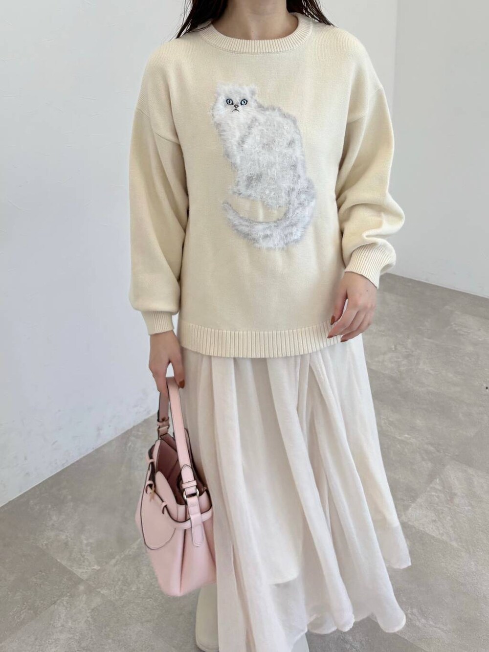 ピンク系のショルダーバッグ、ホワイト系のブーツ、ホワイト系のスカートを着用したレディースの冬コーディネートの3枚目の写真