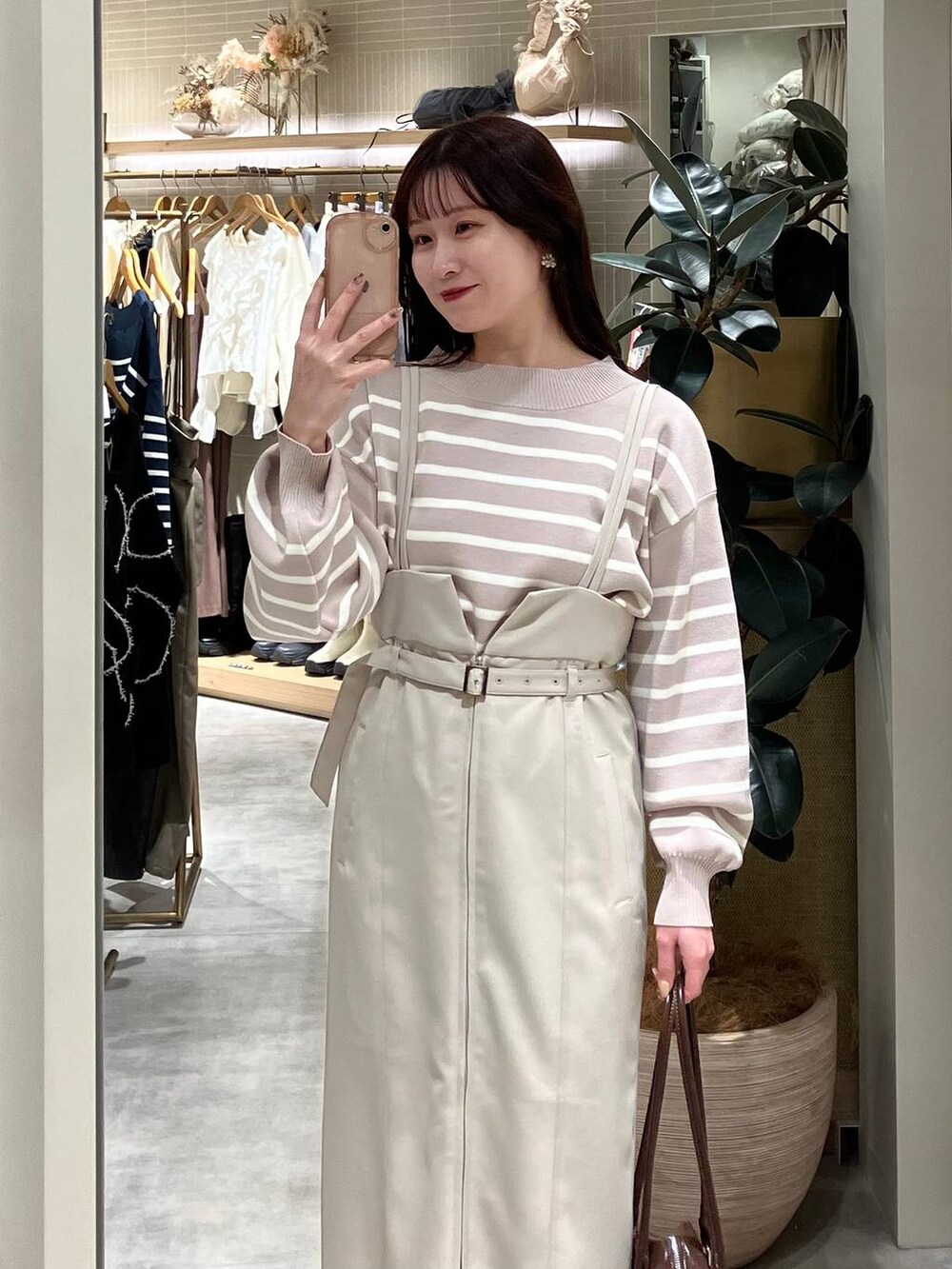 ブラウン系のブーツ、ブラウン系のハンドバッグ、ベージュ系のニット/セーターを着用したレディースの冬コーディネートの2枚目の写真