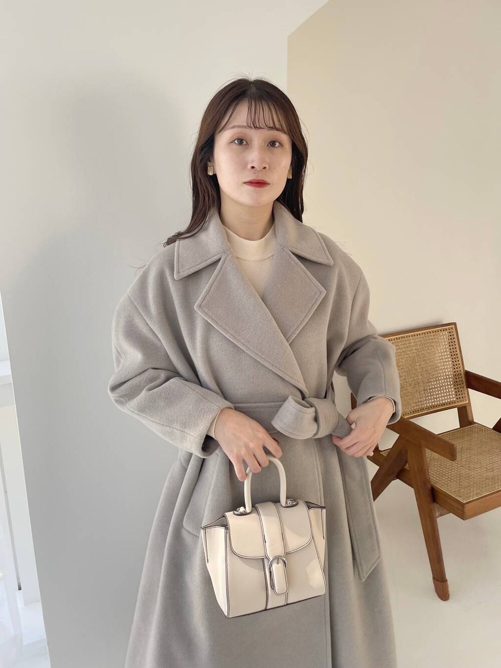 ホワイト系のハンドバッグ、ホワイト系のブーツ、ホワイト系のニット/セーターを着用したレディースの秋コーディネートの3枚目の写真