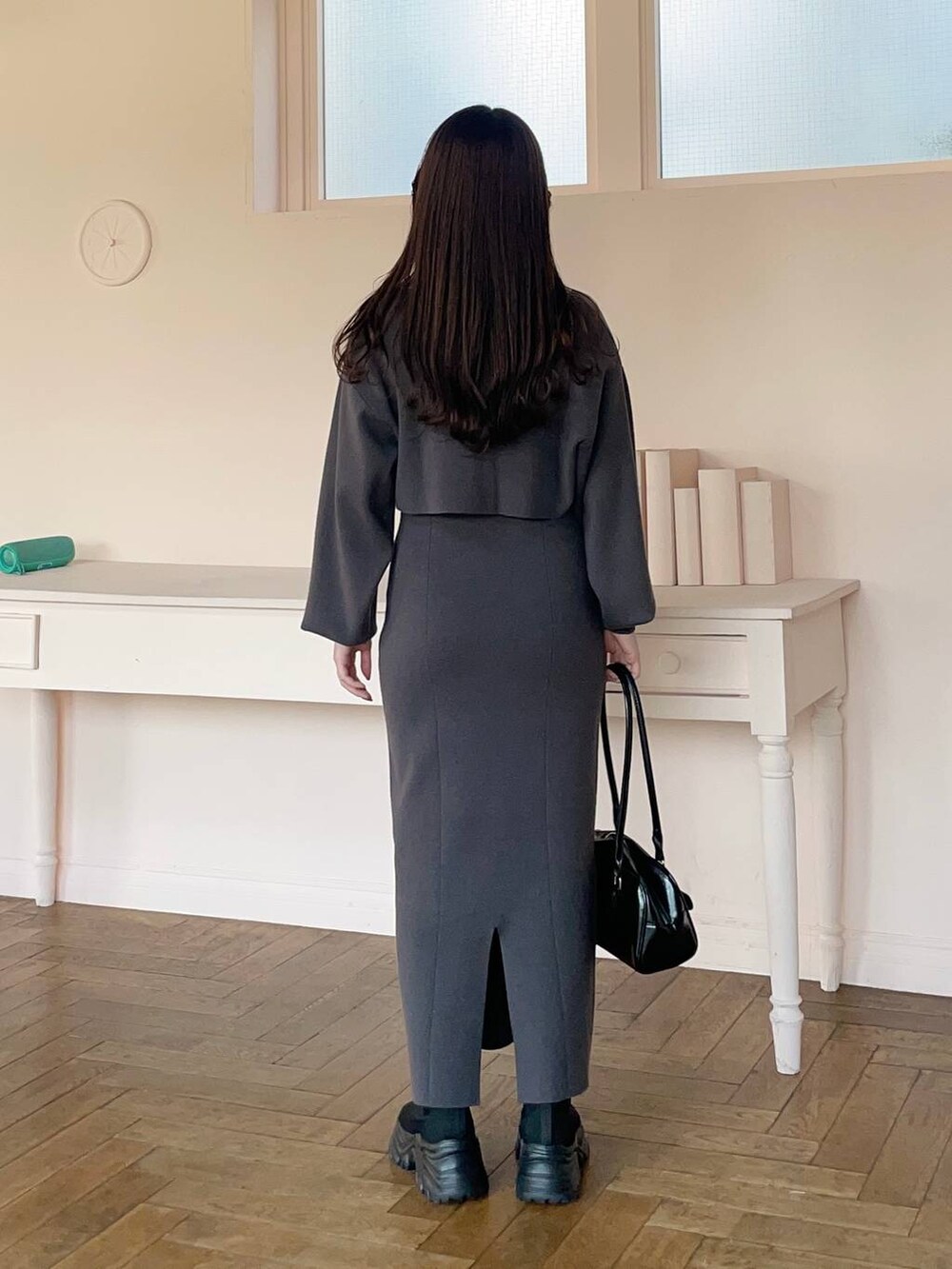 ブラック系のブーツ、グレー系のワンピース、ブラック系のハンドバッグを着用したレディースの冬コーディネートの2枚目の写真