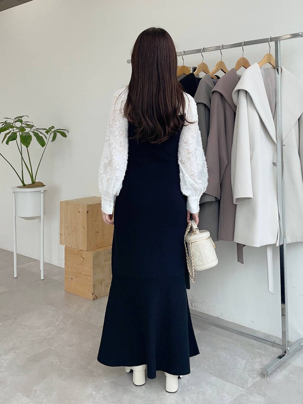 ブラック系のその他アウター、ホワイト系のブーツ、ホワイト系のショルダーバッグを着用したレディースの秋コーディネートの4枚目の写真