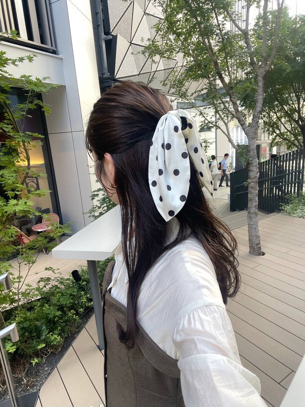 ブラウン系のワンピース、ベージュ系のハンドバッグ、ベージュ系のキーホルダーを着用したレディースの秋コーディネートの3枚目の写真