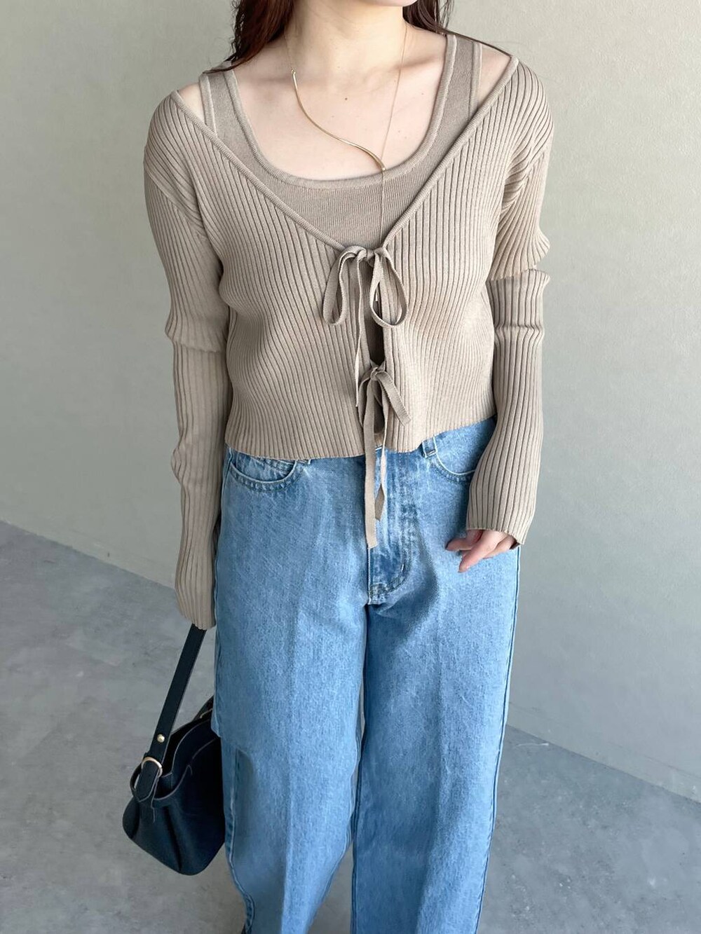 ブラック系のショルダーバッグ、ブルー系のデニムパンツ、ブラック系のパンプスを着用したレディースの冬コーディネートの3枚目の写真