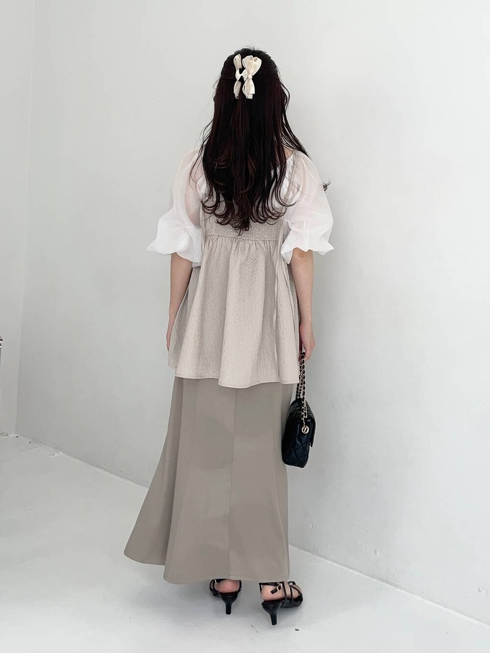 グリーン系のスカート、ホワイト系のTシャツ/カットソー、ブラック系のショルダーバッグを着用したレディースの夏コーディネートの2枚目の写真