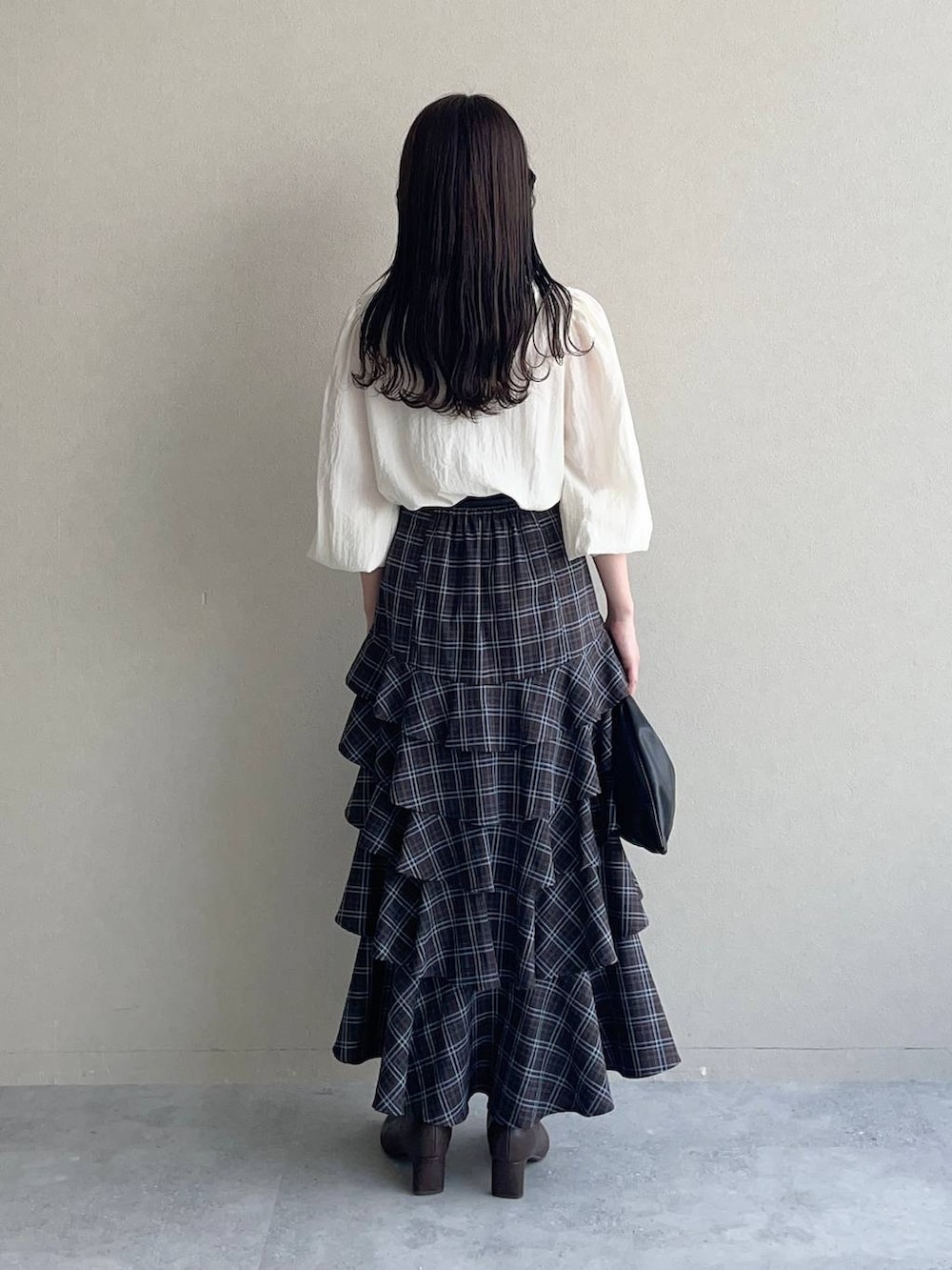 ブラック系のハンドバッグ、ホワイト系のTシャツ/カットソー、ブラウン系のスカートを着用したレディースの秋コーディネートの2枚目の写真