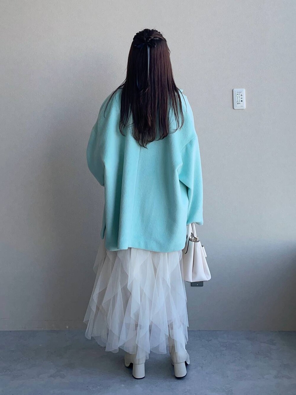 ホワイト系のブーツ、ホワイト系のショルダーバッグ、グリーン系のテーラードジャケットを着用したレディースの冬コーディネートの2枚目の写真