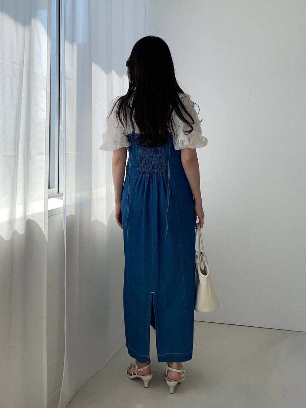 ホワイト系のハンドバッグ、ブルー系のワンピース、ホワイト系のサンダルを着用したレディースの夏コーディネートの3枚目の写真