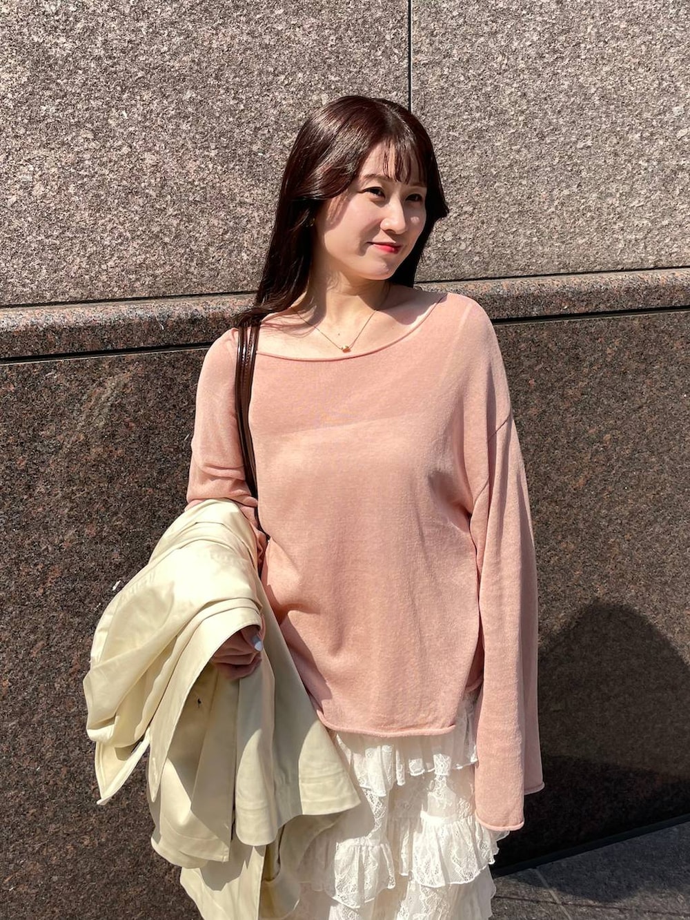 ピンク系のニット/セーター、ブラウン系のハンドバッグ、ベージュ系のトレンチコートを着用したレディースの春コーディネートの3枚目の写真