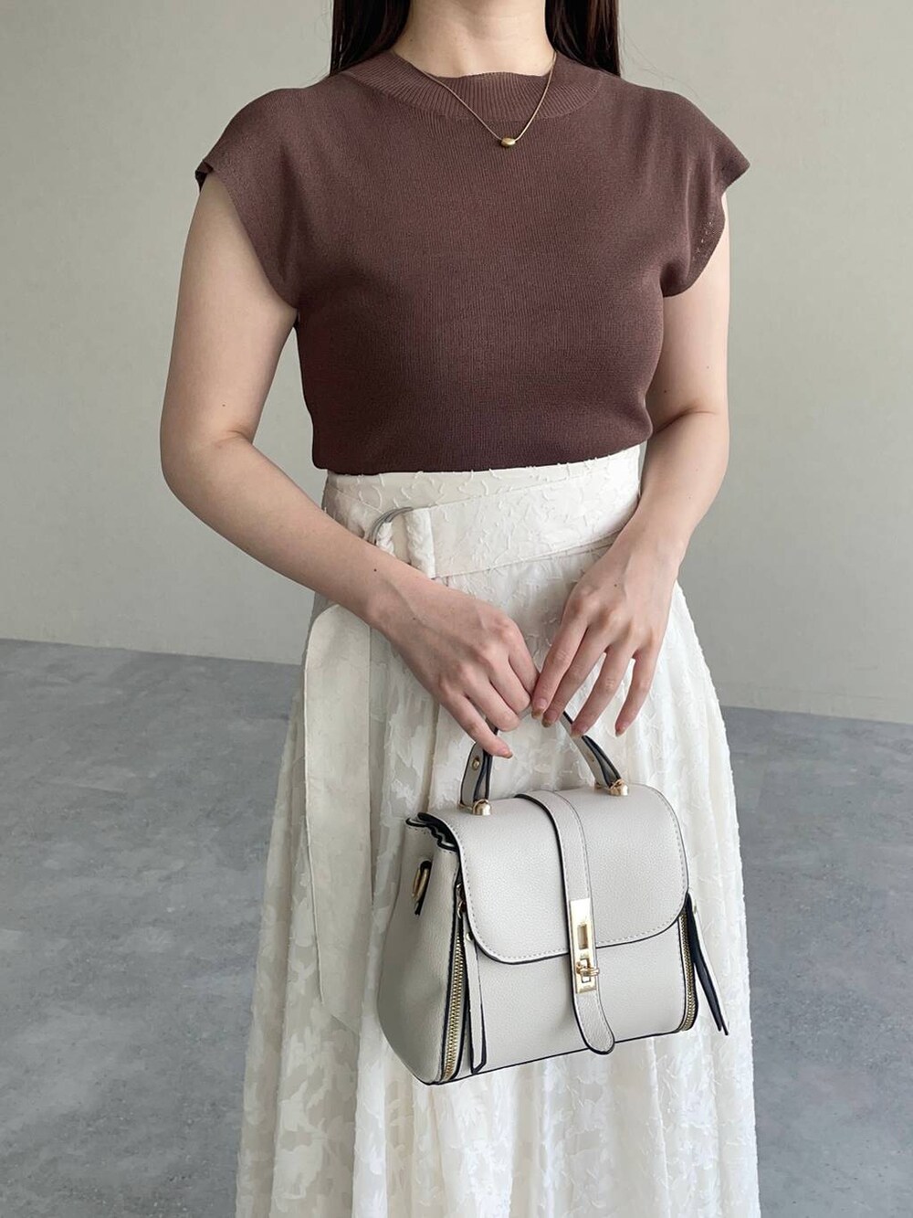 ホワイト系のショルダーバッグ、ブラウン系のニット/セーター、ホワイト系のスカートを着用したレディースの夏コーディネートの3枚目の写真