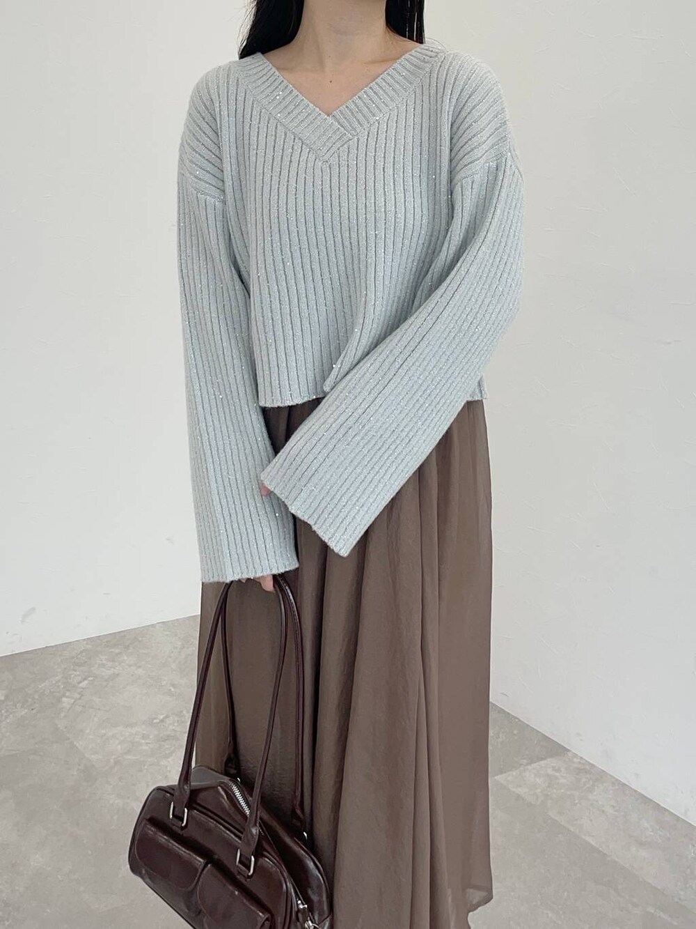 ホワイト系のブーツ、ブラウン系のハンドバッグ、ブラウン系のスカートを着用したレディースの冬コーディネートの3枚目の写真