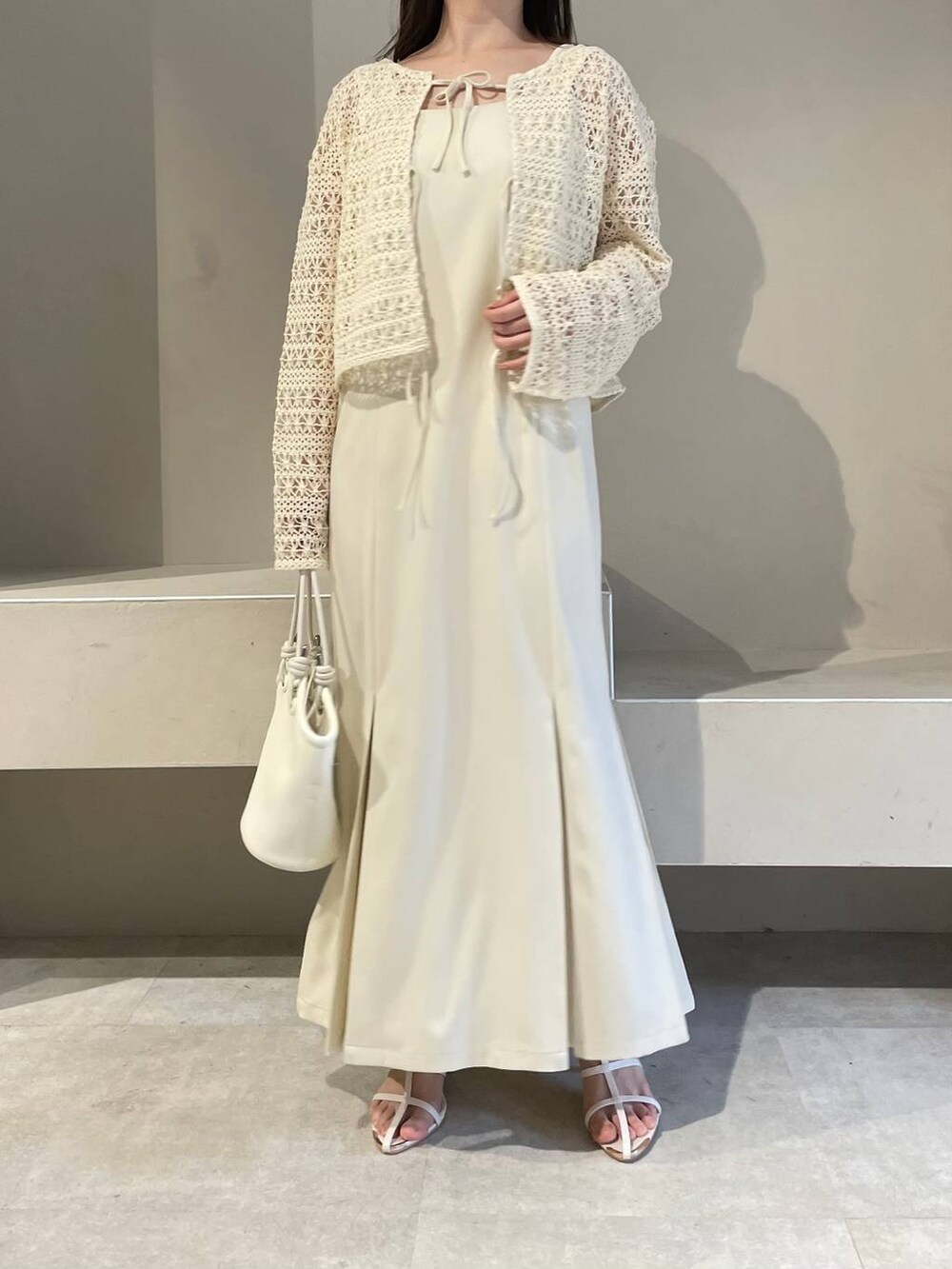 ホワイト系のハンドバッグ、ホワイト系のカーディガン/ボレロ、ホワイト系のサンダルを着用したレディースの春コーディネートの3枚目の写真