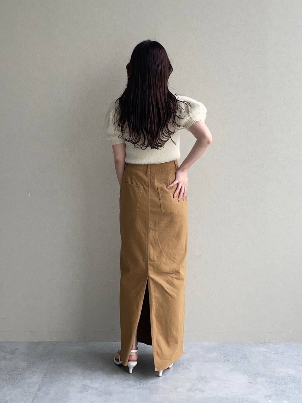 ベージュ系のニット/セーター、ホワイト系のサンダル、ブラウン系のスカートを着用したレディースの夏コーディネートの2枚目の写真