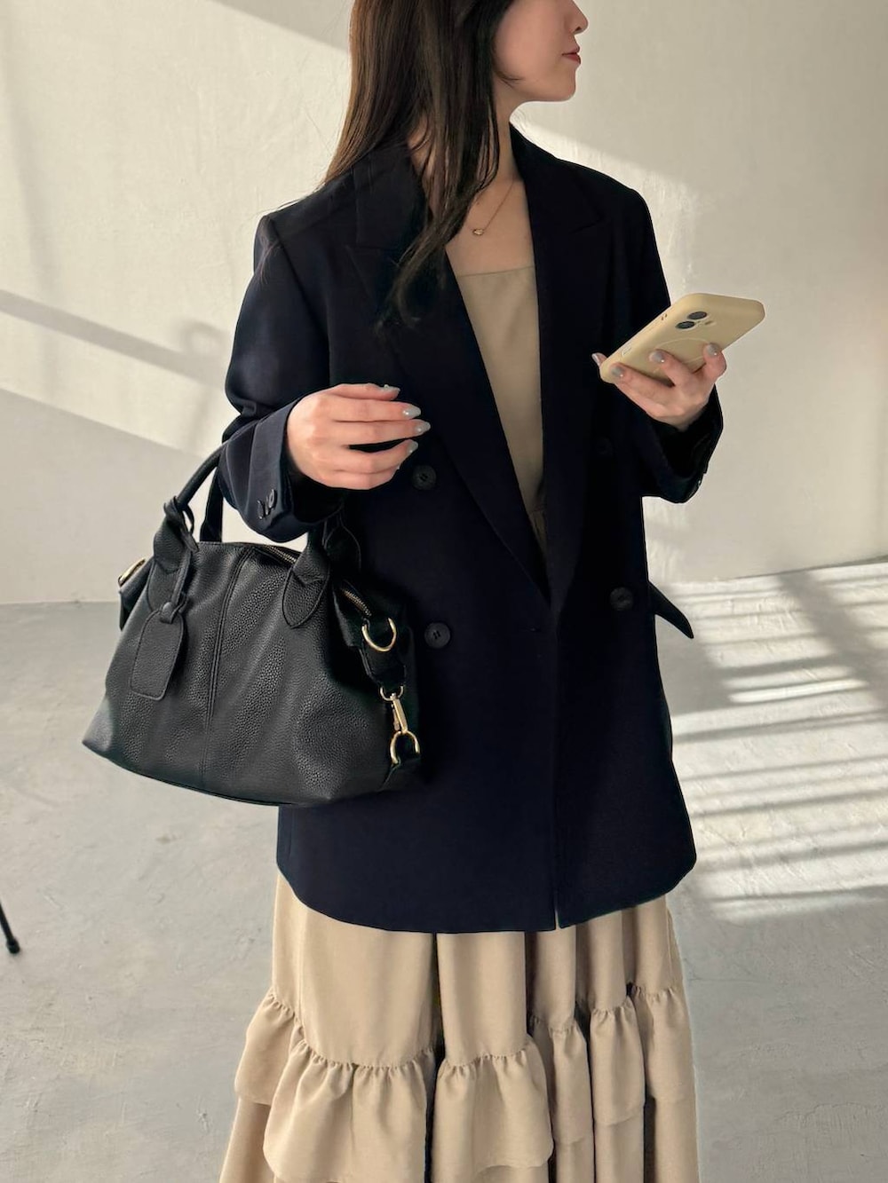 ブラック系のボストンバッグ、ブルー系のテーラードジャケット、ブラック系のサンダルを着用したレディースの冬コーディネートの3枚目の写真