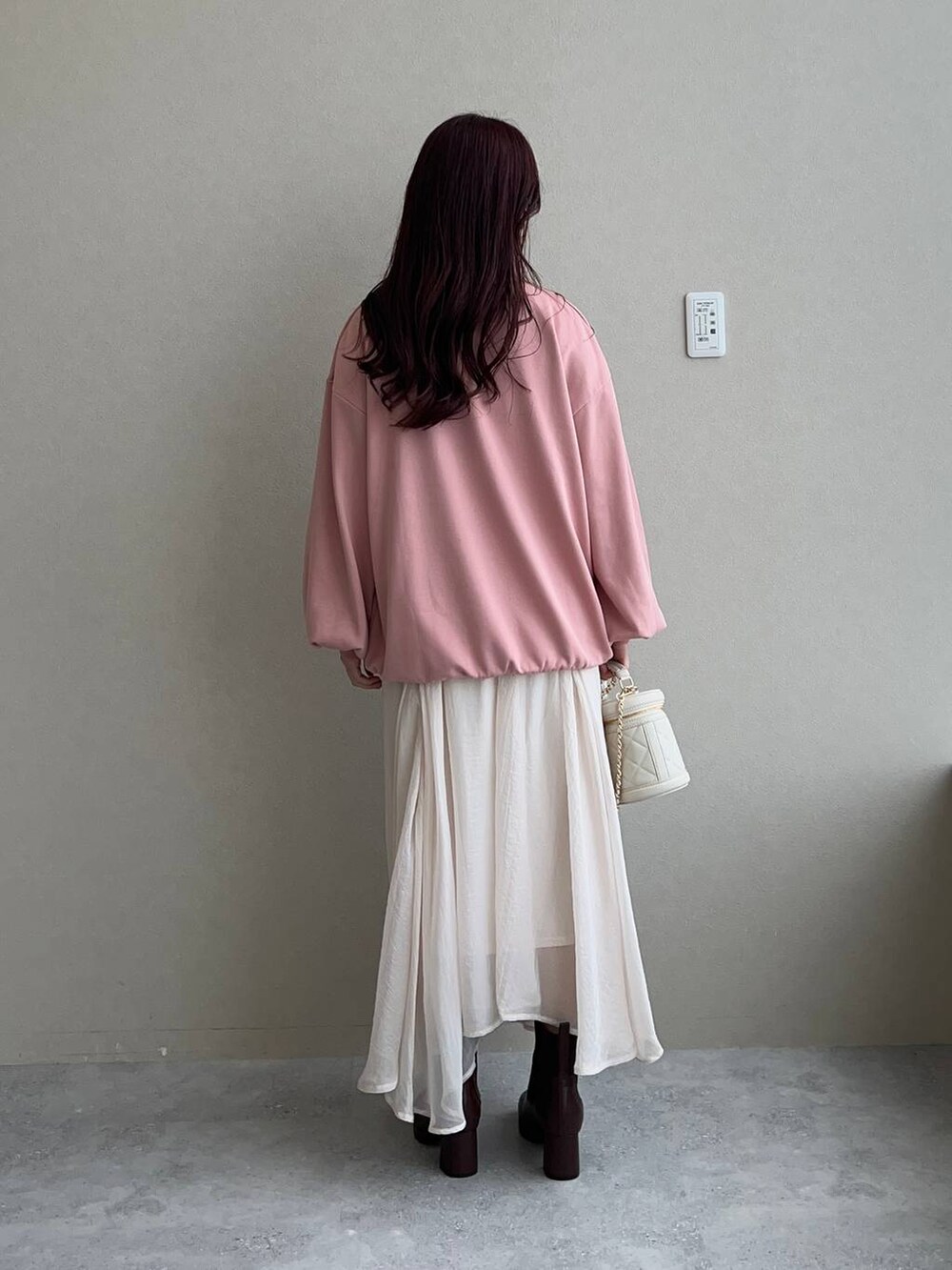 ブラウン系のブーツ、ピンク系のスウェット、ホワイト系のショルダーバッグを着用したレディースの秋コーディネートの3枚目の写真