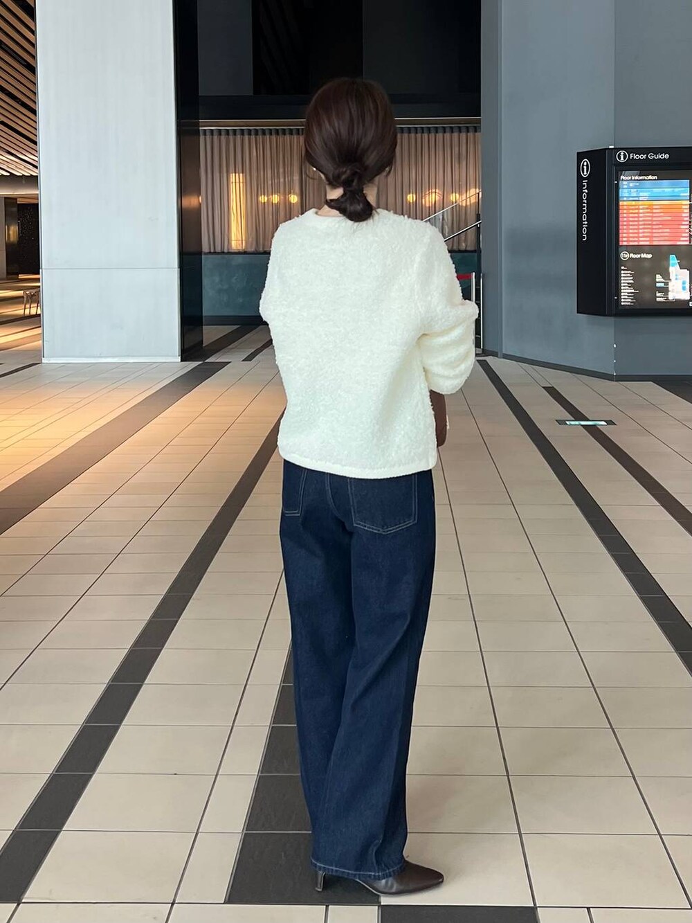 ホワイト系のカーディガン/ボレロ、ブルー系のデニムパンツ、ブラウン系のブーツを着用したレディースの秋コーディネートの2枚目の写真