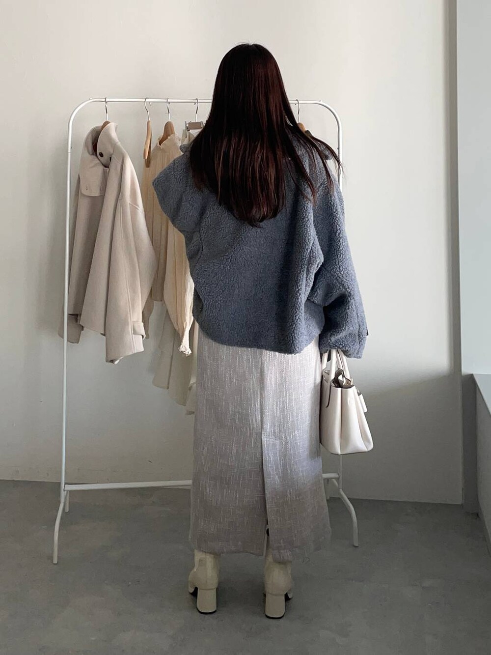 グレー系のピーコート、ホワイト系のブーツ、ホワイト系のニット/セーターを着用したレディースの冬コーディネートの2枚目の写真