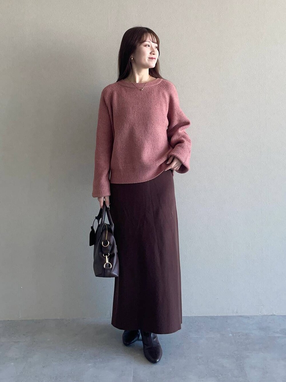 ピンク系のニット/セーター、ブラウン系のボストンバッグ、ホワイト系のチェスターコートを着用したレディースの冬コーディネートの3枚目の写真