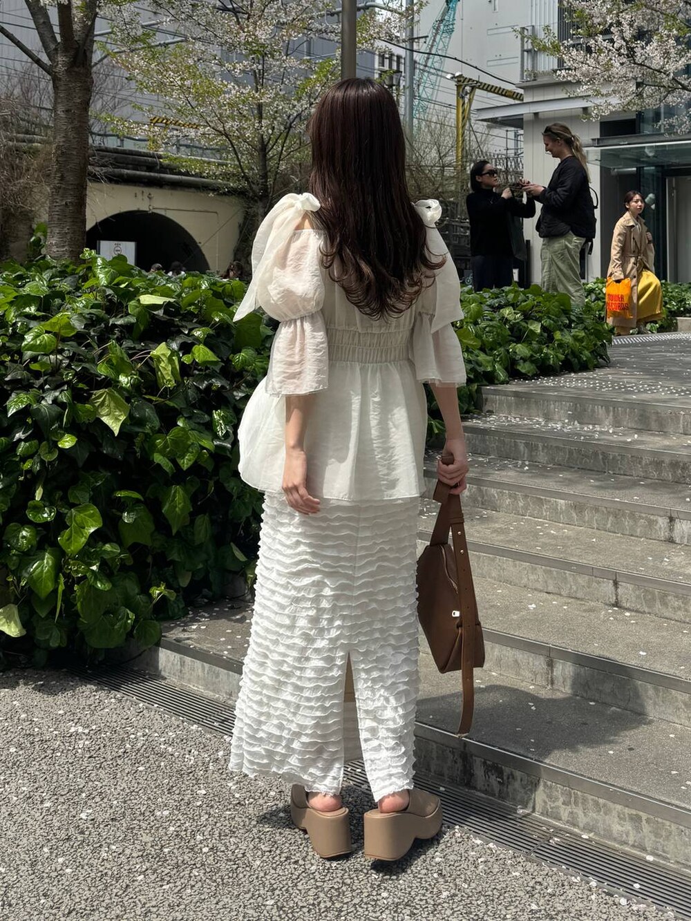 ベージュ系のサンダル、ホワイト系のスカート、ブラウン系のショルダーバッグを着用したレディースの春コーディネートの2枚目の写真