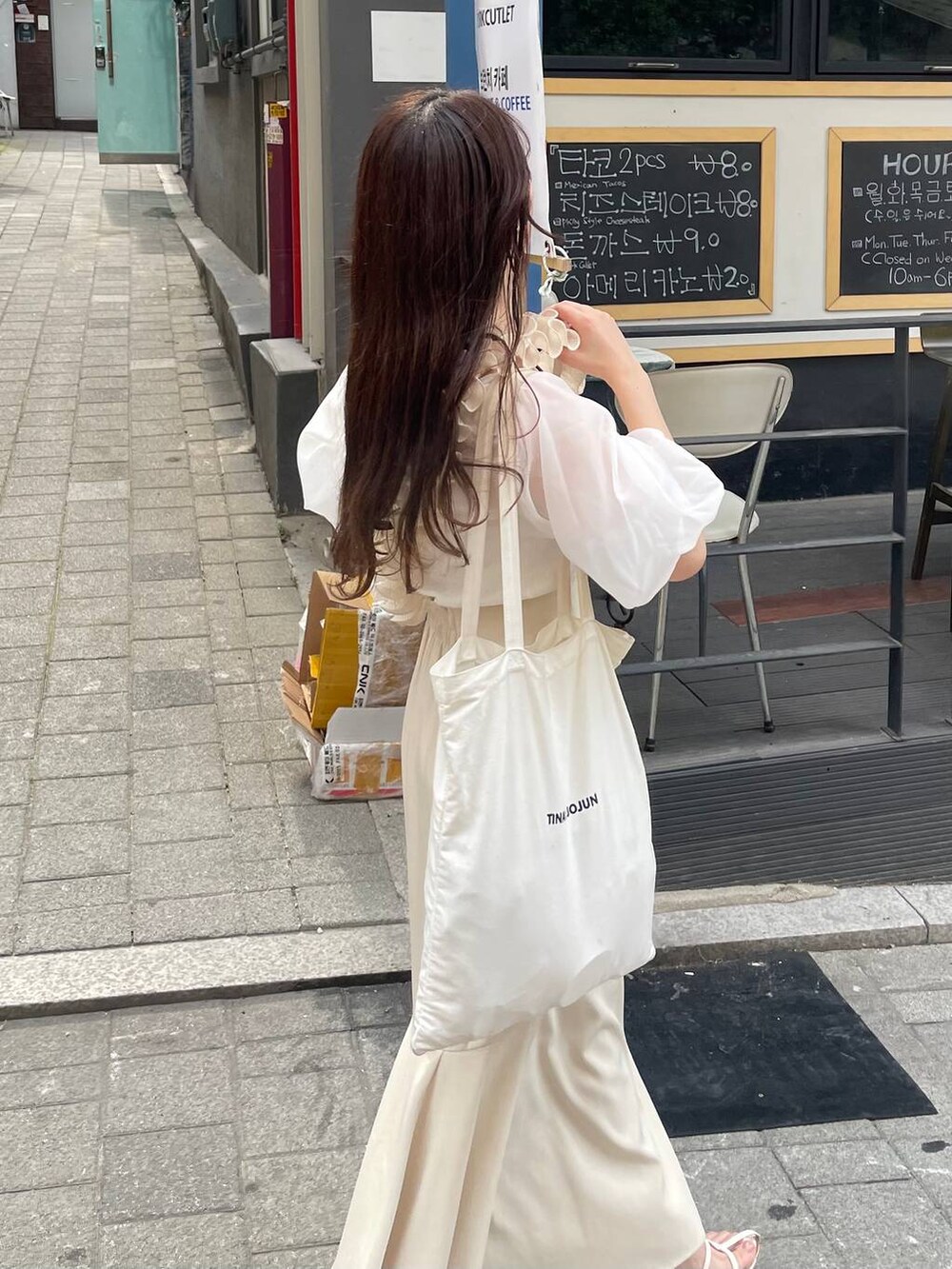 ホワイト系のTシャツ/カットソー、ホワイト系のサンダル、ホワイト系のスマホグッズを着用したレディースの夏コーディネートの3枚目の写真