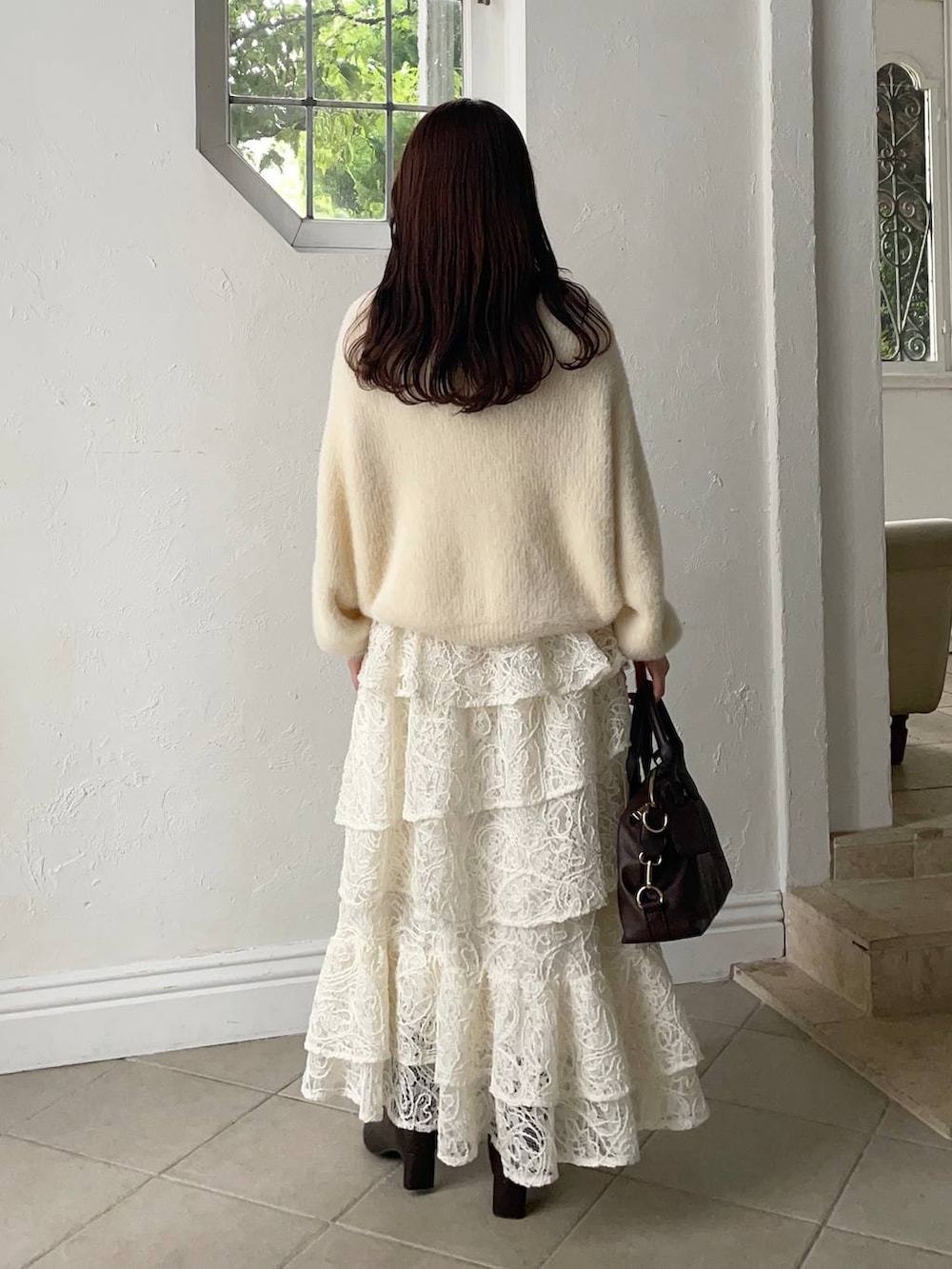 ブラウン系のボストンバッグ、ブラウン系のマウンテンパーカー、ホワイト系のスカートを着用したレディースの秋コーディネートの4枚目の写真