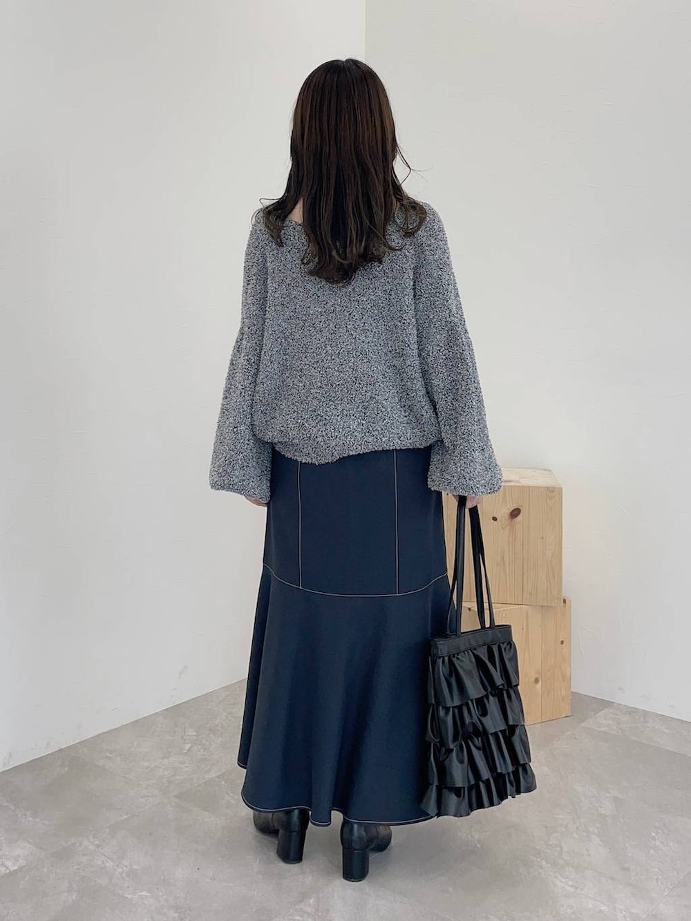 ブラック系のブーツ、グレー系のスカート、ブラック系のトートバッグを着用したレディースの秋コーディネートの2枚目の写真