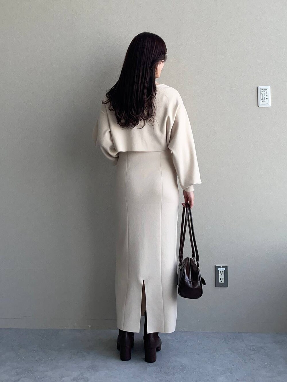 ブルー系のチェスターコート、ブラウン系のブーツ、ホワイト系のワンピースを着用したレディースの冬コーディネートの4枚目の写真