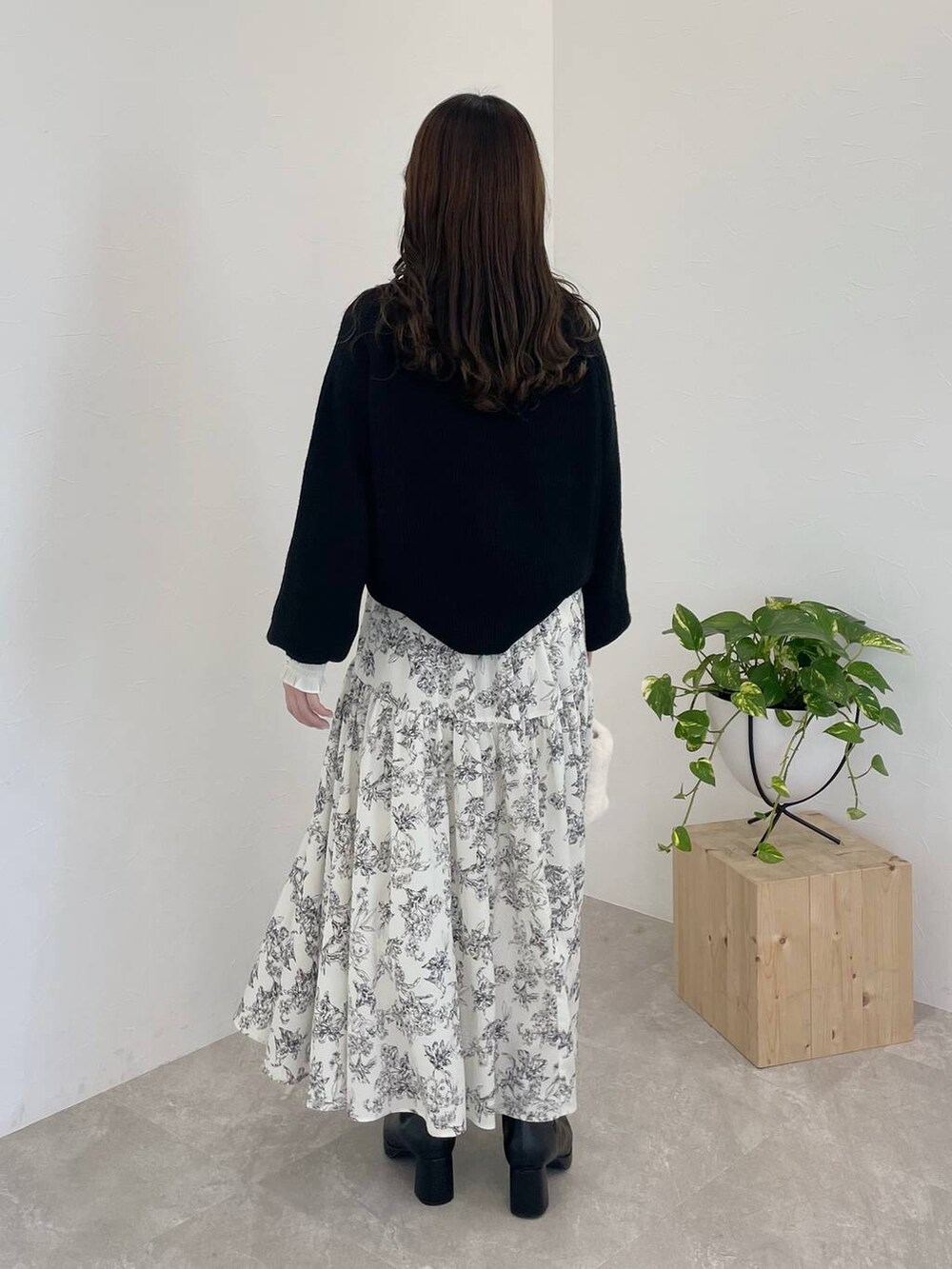 ブラック系のニット/セーター、ブラック系のブーツ、ホワイト系のハンドバッグを着用したレディースの冬コーディネートの2枚目の写真