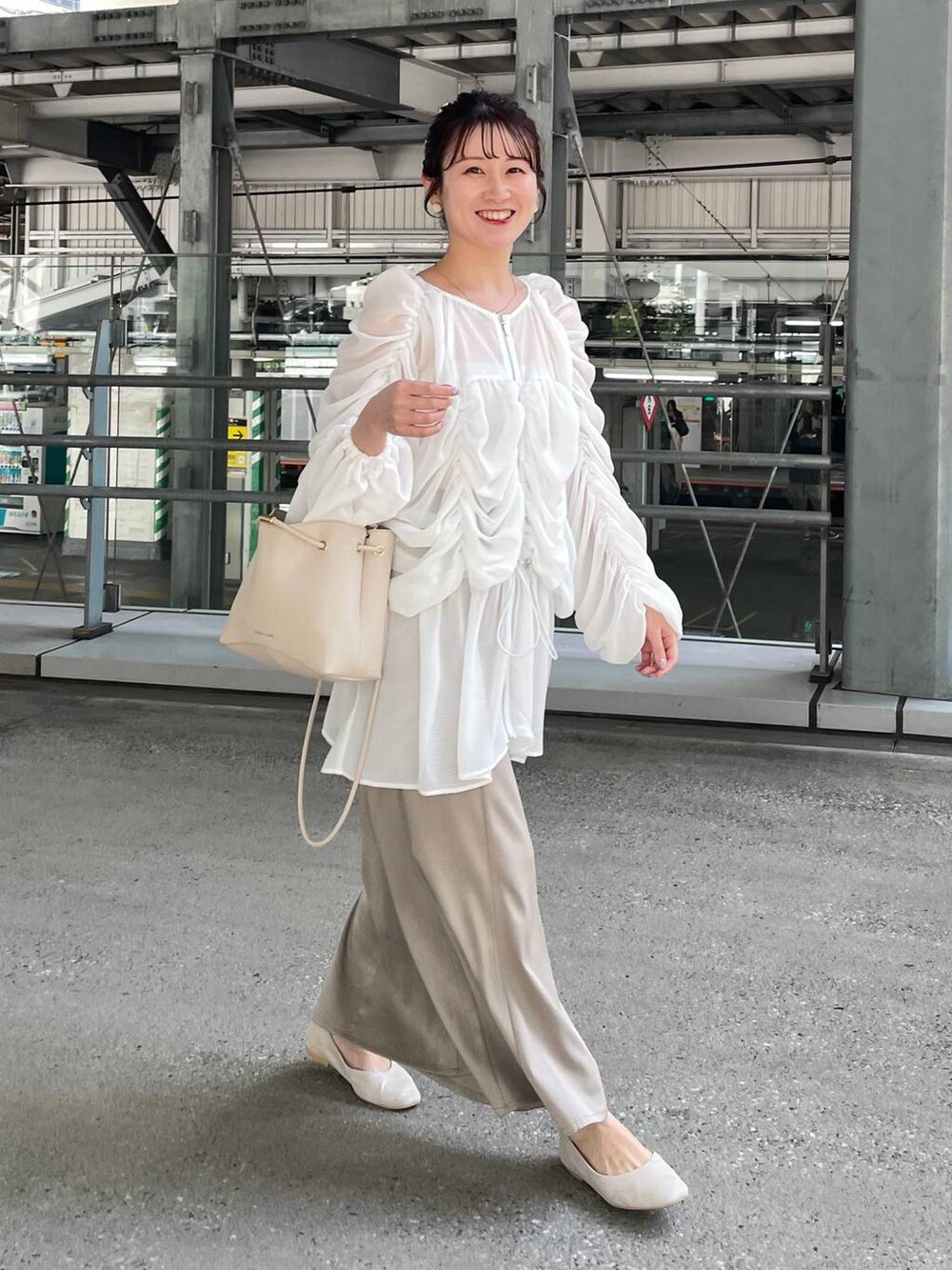 ベージュ系のスカート、ベージュ系のパンプス、ホワイト系のシュシュを着用したレディースの春コーディネートの2枚目の写真