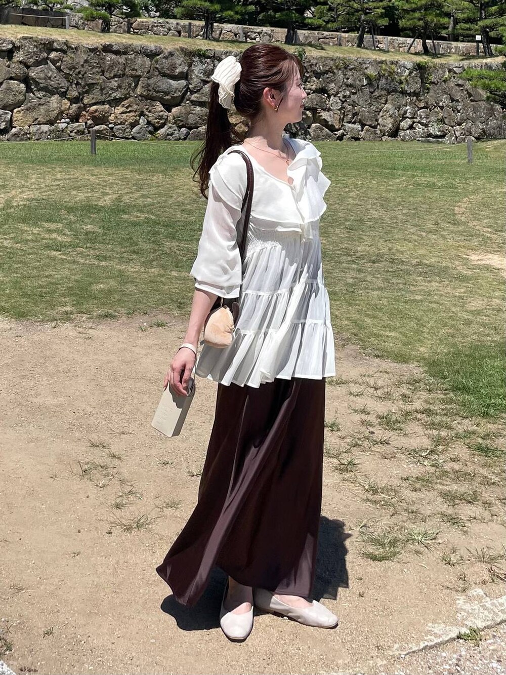ブラウン系のスカート、ホワイト系のシャツ/ブラウス、ベージュ系のシュシュを着用したレディースの夏コーディネートの3枚目の写真