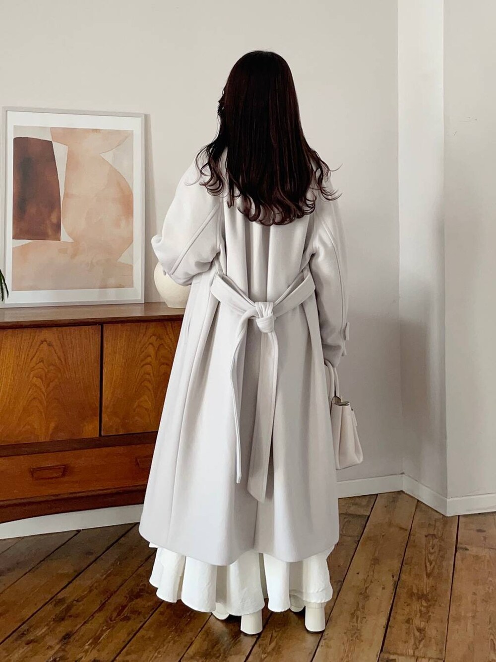 ホワイト系のチェスターコート、ホワイト系のブーツ、ホワイト系のスカートを着用したレディースの冬コーディネートの2枚目の写真