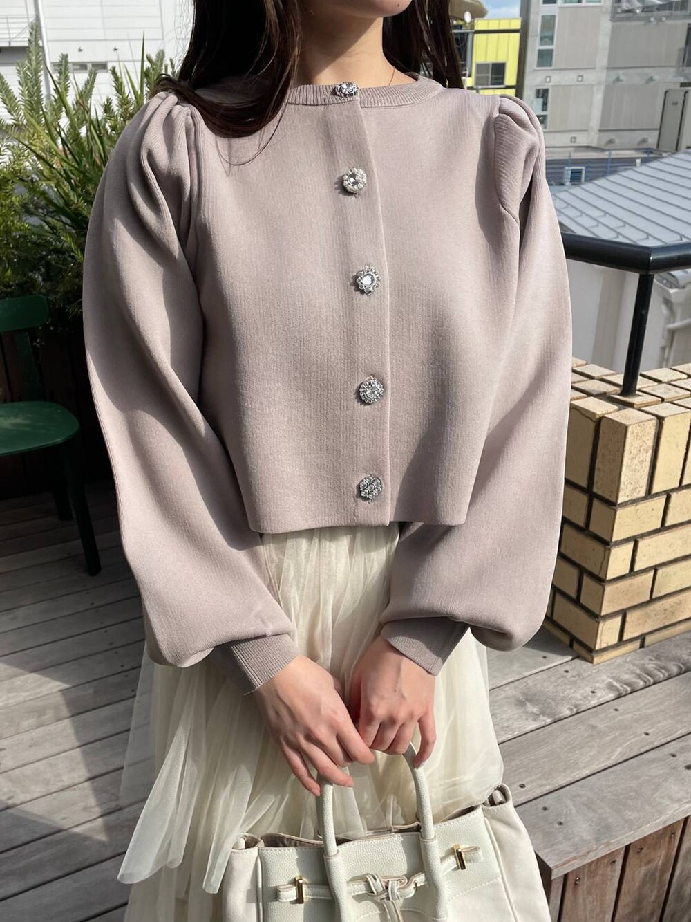 ベージュ系のカーディガン/ボレロ、ホワイト系のトートバッグ、ホワイト系のスカートを着用したレディースの冬コーディネートの3枚目の写真